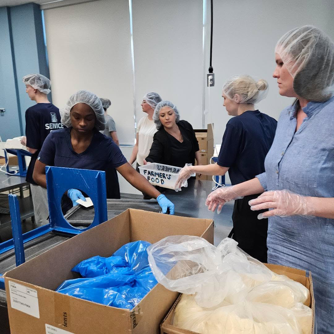 Teammates volunteering and packaging food for those in need